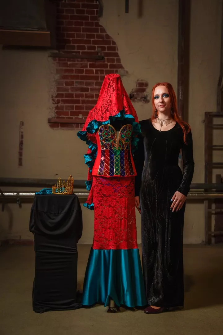 Studentka stoi przy swoim projekcie sukni