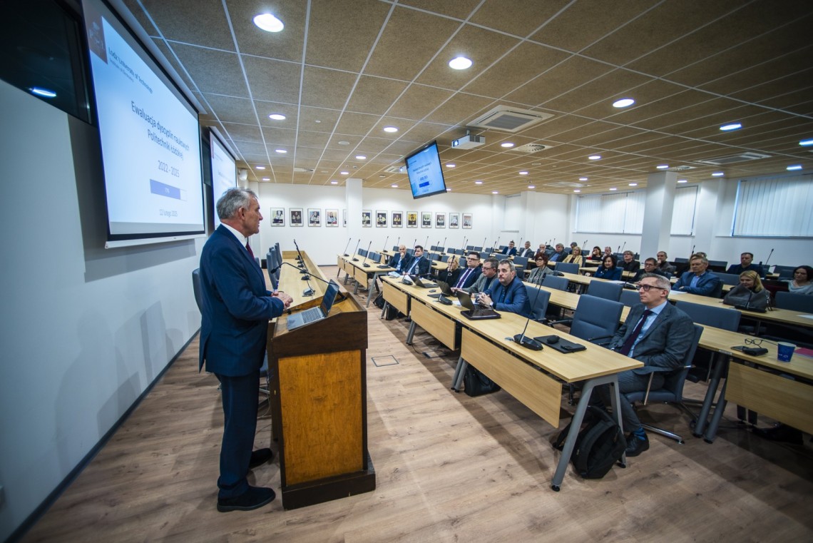 Za mównicą stoi mężczyzna i przemawia do osób siedzących w sali seminaryjnej