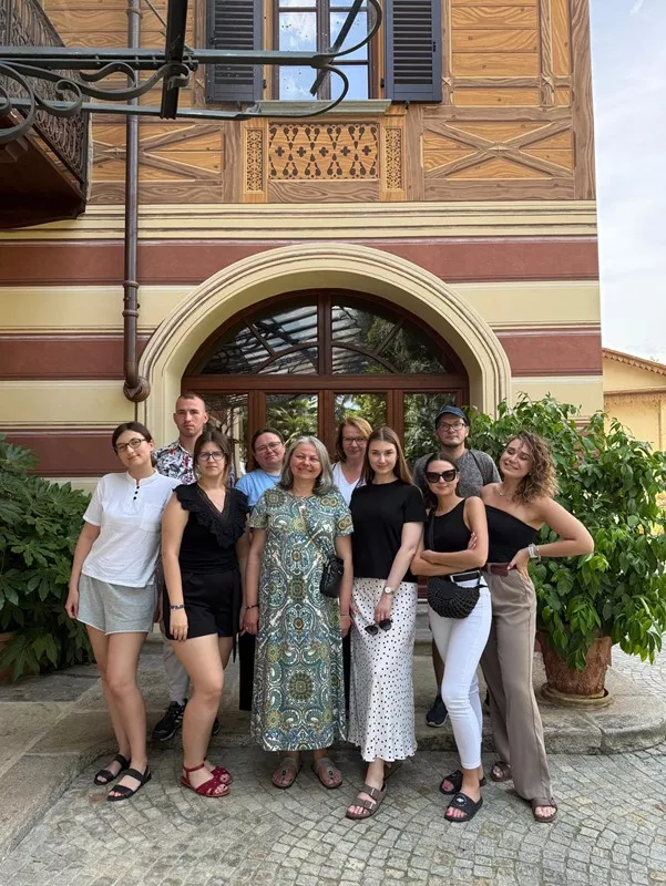 Kilka osób stoi na tle dekoracyjnej elewacji budynku