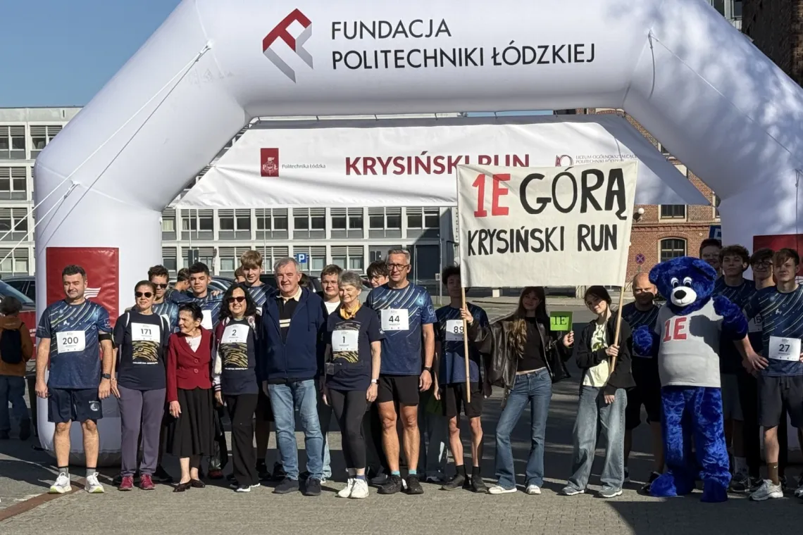 Grupa osób w koszulkach, dwie trzymające transparent, stoją na stracie biegu