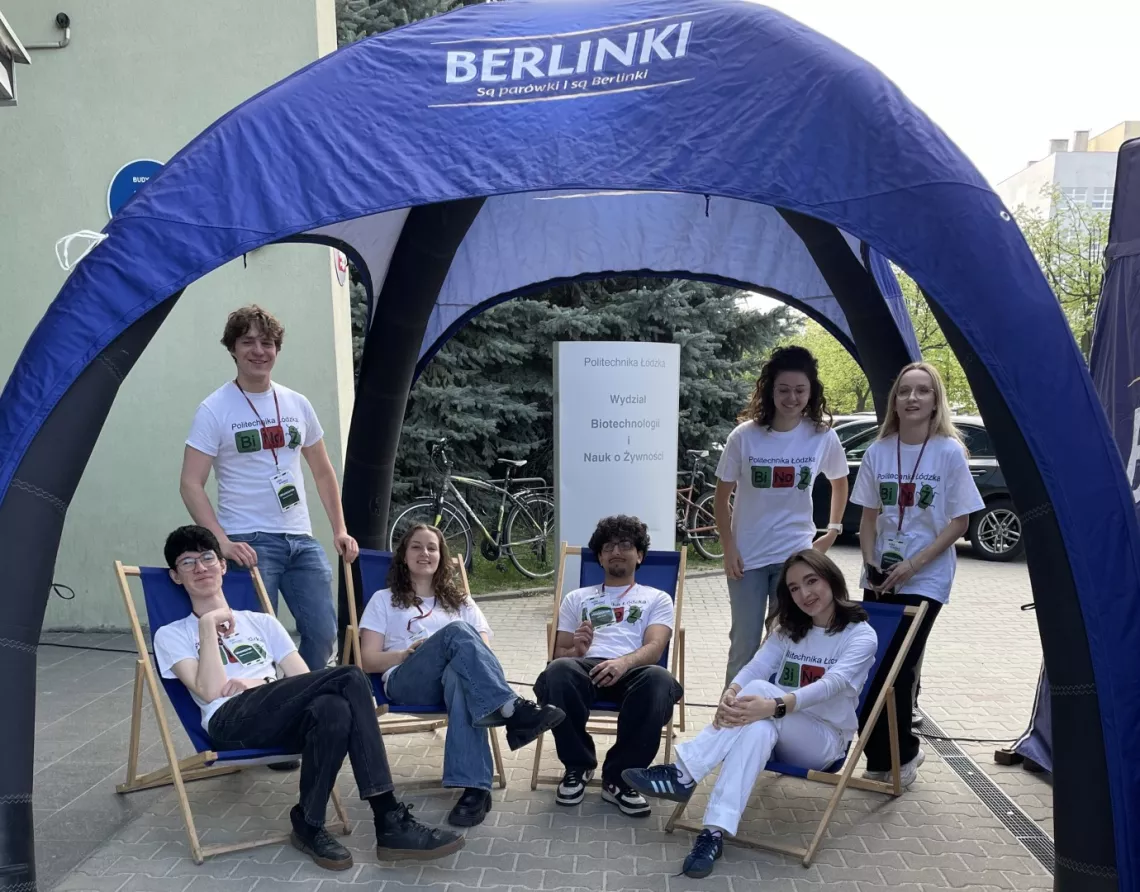 Kilka osób siedzi na leżakch i stoi pod otwartm namiotem z napisem Berlinki