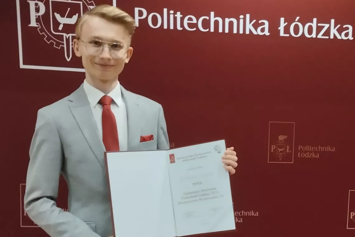 Młody mężczyzna w szarym garniturze pokazuje rozłożony dokument