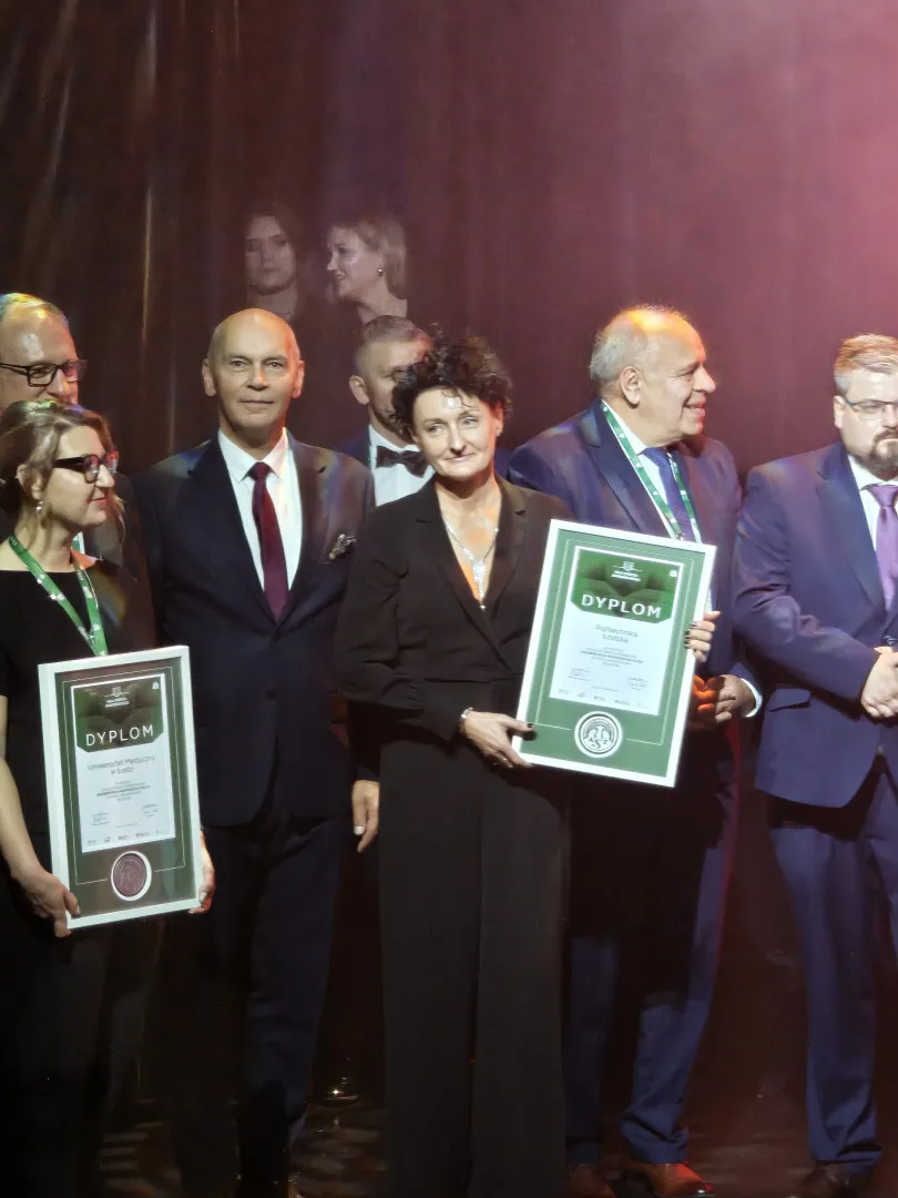 Kilka osób na scenie, dwie z nich trzymają dyplomy