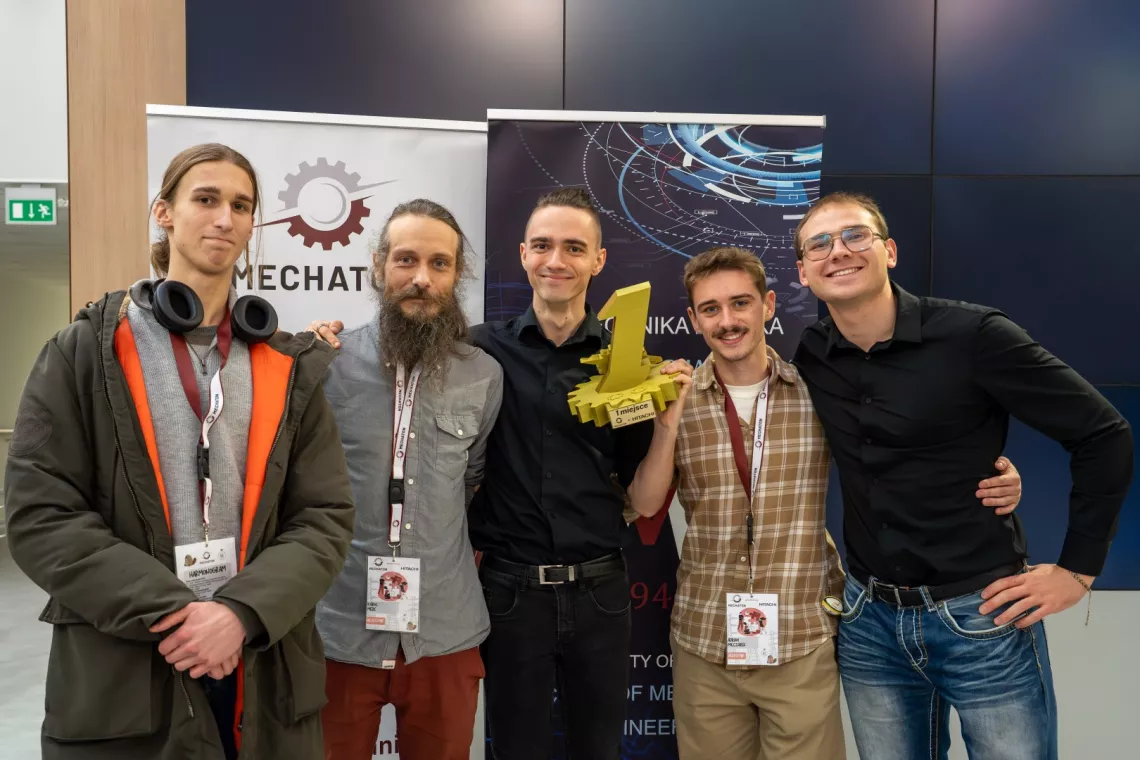 Pięciu studentów pozuje do zdjęcia, jeden z nich trzyma w ręku cyfrę 1