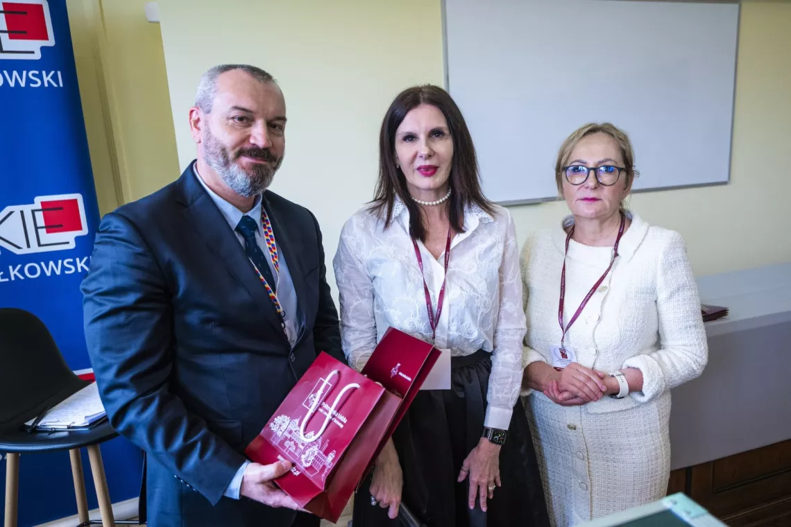 Dwie kobiety i mężczyzna trzymający torbę prezentową PŁ