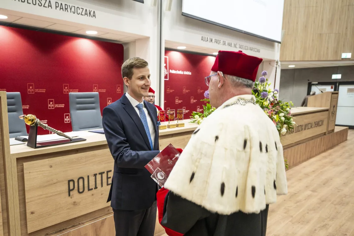 Młody mężczyzna otrzymuje nagrodę od rektora