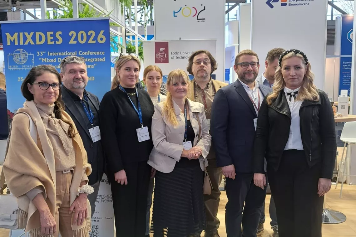 Dziwięć osób stoi na tle banerów umieszczonych na targowym stoisku