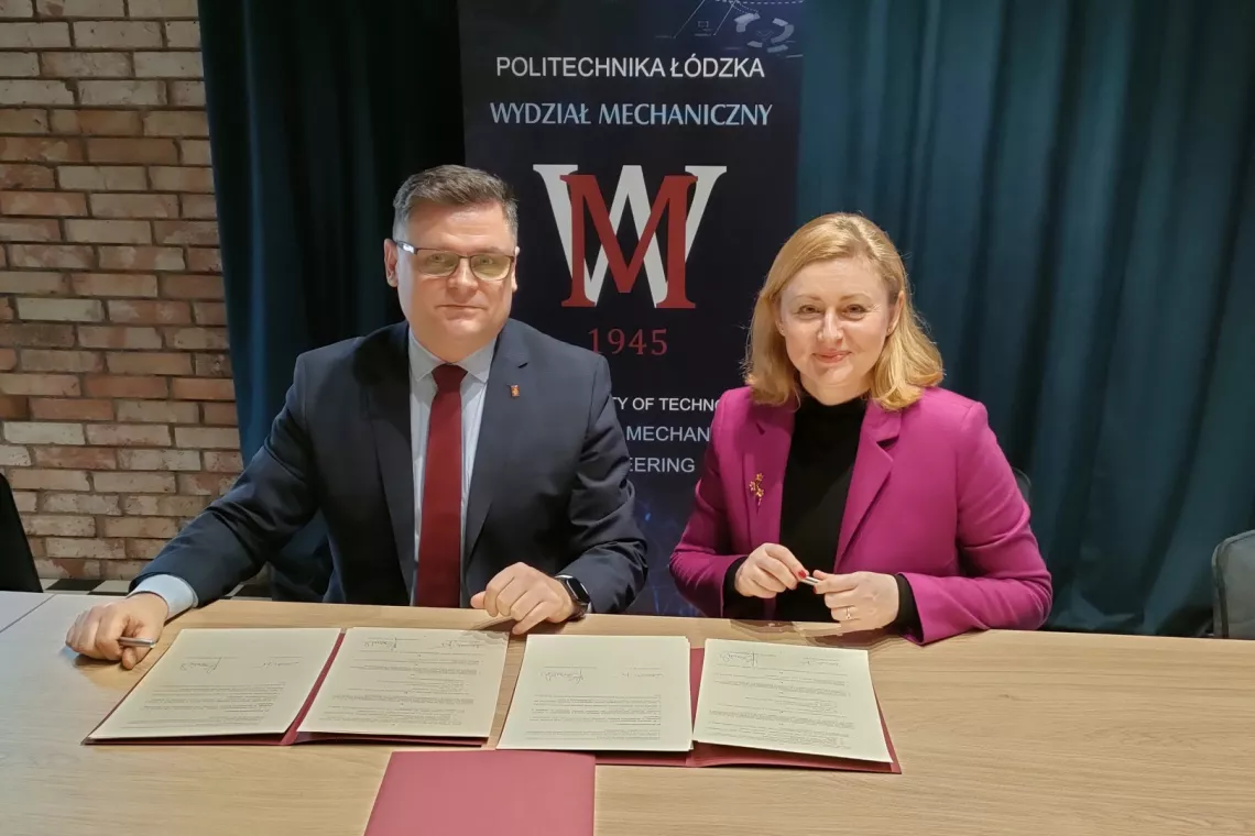 Dwie osoby podpisujące pzry stole dokument umowy. W tle baner z napisem Politechnika Łódzka Wydział Mechaniczny.