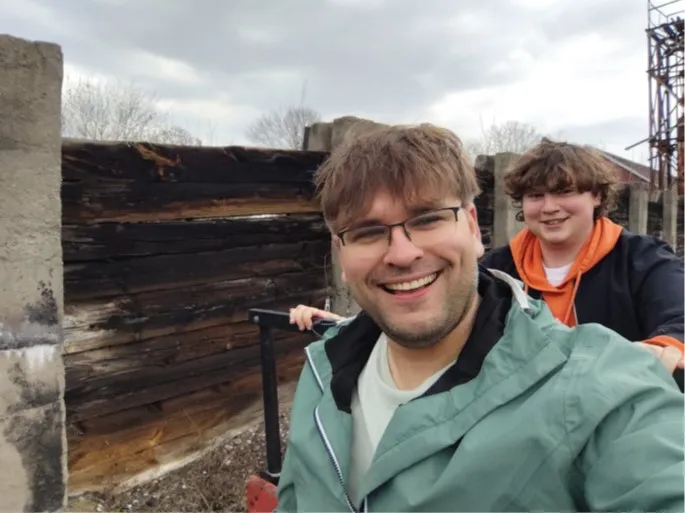 Dwóch usmiechniętych młodych mężczyzn, zdjęcie typu selfie, jadą na drezynie