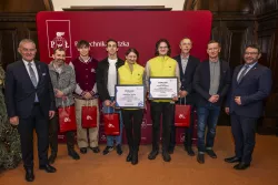 Dziewięc osób, w tym dwie w żóltych kamizelkach, stoją na tle ścianki z napisem Politechnika Łódzka