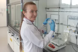 Badaczka w białym fartuchu i ochronnych rękawiczkach w laboratorium chemicznym trzyma w reku próbkę