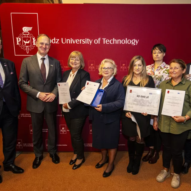 Osiem osób stoi na tle ścianki z napisem  Lodz University of Technology, sześć z nich trzyma dyplomy, a także symboliczny czek i statuetki