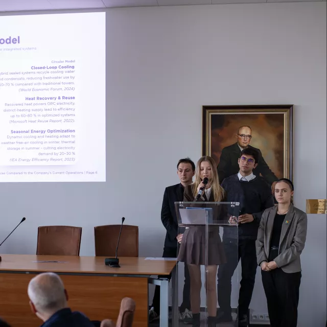 Cztery osoby prezentują projekt, jedna z nich przemawia do mikrofonu