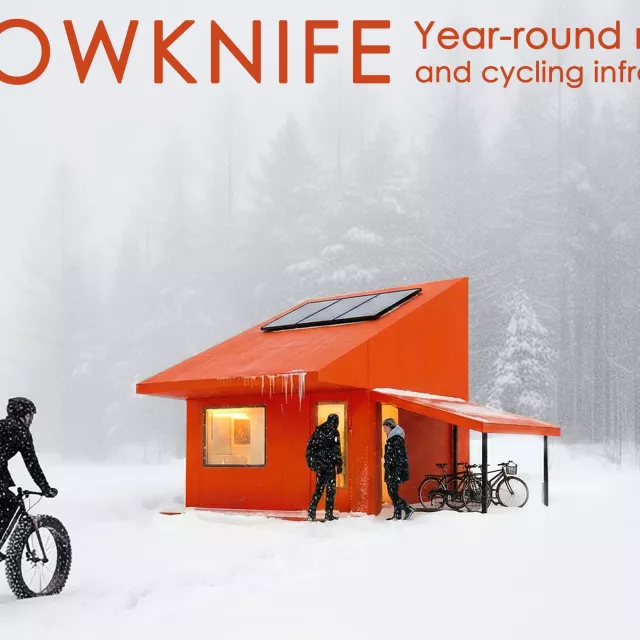 Pomarańczowy domek z panelem słonecznym na dachu, daszkiem nad wejsciem. Przy domku stoją rowerzyści, a kolejny zbliża się