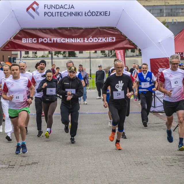 Grupa osób startujących w biegu, w tle dmuchaniec z napisem Bieg Politechniki Łódzkie Fundacja Politechniki Łódzkiej 